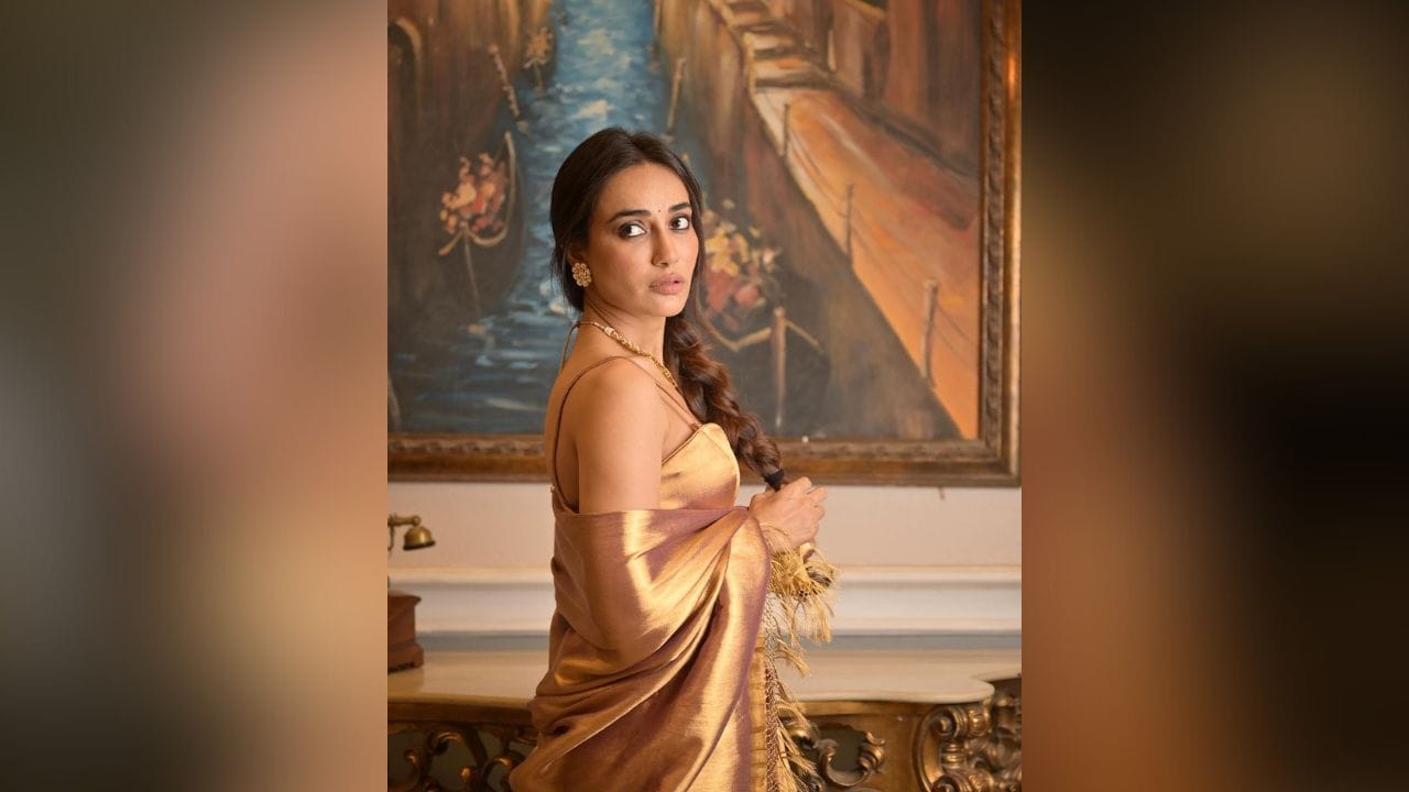 આ લેટેસ્ટ ફોટોઝમાં સુરભી જ્યોતિએ ગોલ્ડન કલરની સિમ્પલ સાટીન સાડી પહેરી છે અને એક જ દોરી પર બાંધેલો બ્લાઉઝ સાથે કૈરી કર્યો છે. (Image: Instagram)