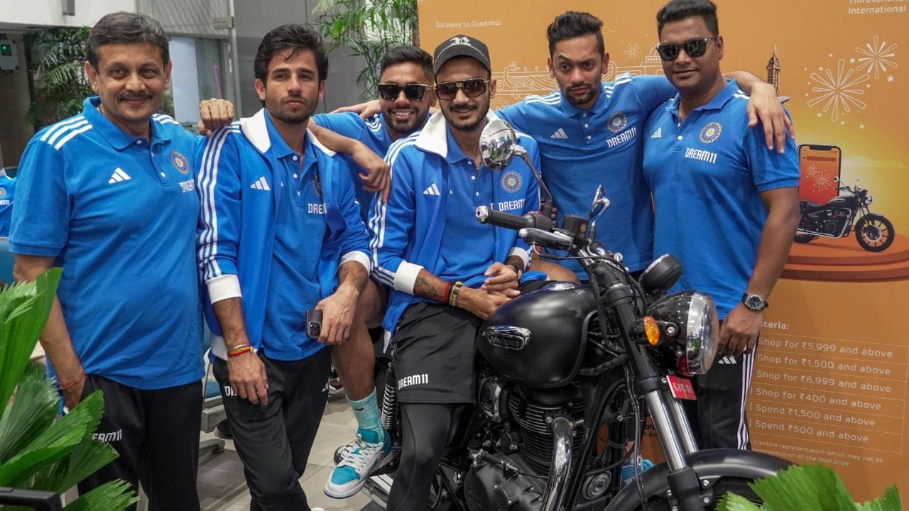 બાઈક પર અક્ષર પટેલ અને પાછળ આવેશ ખાન બેઠા છે તેમની સાથે રવિ બિશનોઈ ઉભો અને અને બીજા પણ કેટલાક લોકો ત્યાં ઉપસ્થિત છે અને ફોટો પડાવી રહ્યા છે.