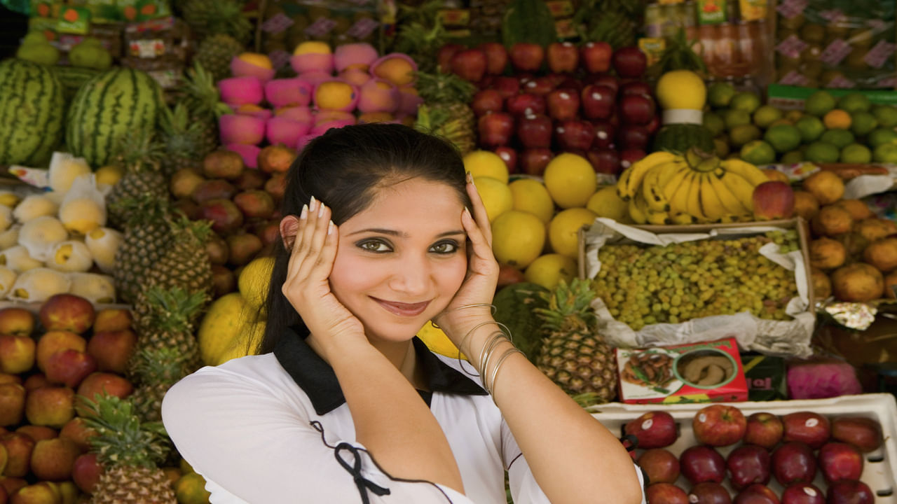Portrait of a Young Woman Standing in Front of a Fruit Stall