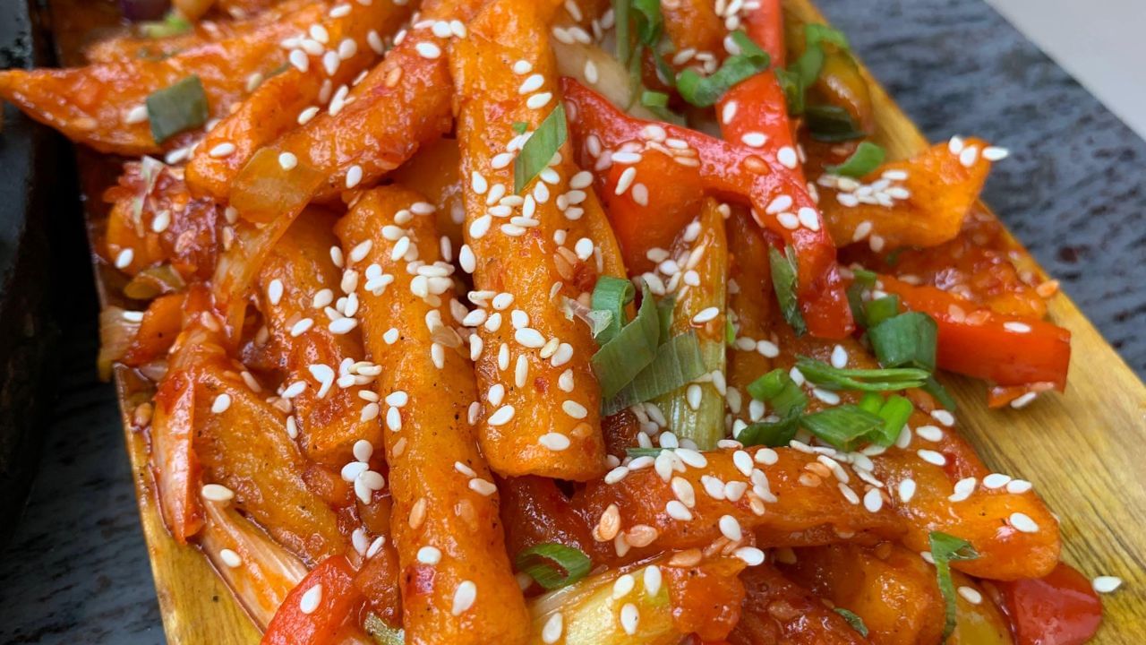 હવે,ગેસ પર એક પેન મૂકો. તેમાં 2 ચમચી તેલ ગરમ કરો. જ્યારે તેલ ગરમ થાય, ત્યારે 1 ચમચી તલ ઉમેરો. તલ થોડી સેકંડમાં શેકાઈ જશે. પછી, 1/2 કપ સિમલા મરચા ઉમેરો અને તેમને મધ્યમ તાપ પર રાંધવા દો. 