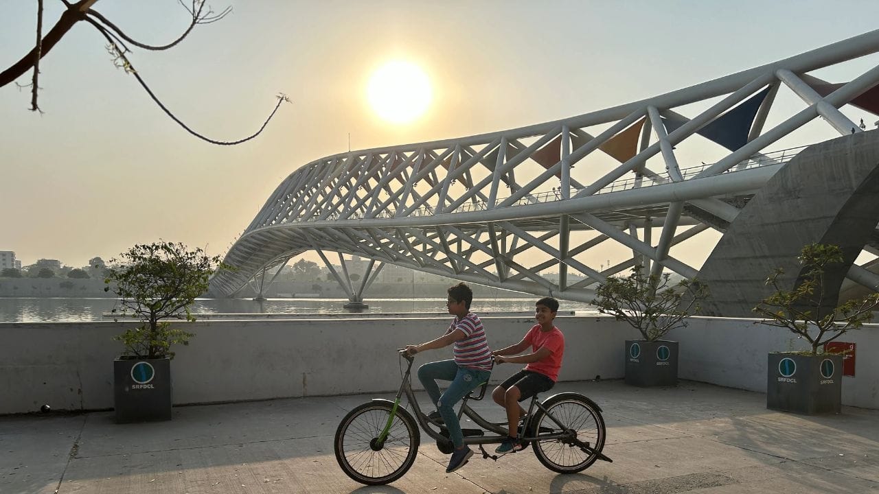 રિવરફ્રન્ટ આધુનિક શહેરોની નવી જીવાદોરી સમાન બની રહી છે. ઘણા લોકો રિવરફ્રન્ટને માત્ર નદીના કિનારે થયેલું બાંધકામ સમજે છે, પણ વાસ્તવમાં તે તેનાથી ઘણું વિશેષ છે. રિવરફ્રન્ટ એ એક એવો કલ્પનાશીલ પ્રોજેક્ટ છે જ્યાં નદીના કિનારાને વ્યવસ્થિત રીતે ડિઝાઇન કરીને શહેરીજનો માટે સુવિધાઓ વિકસાવવામાં આવે છે. તે માત્ર શહેરની સુંદરતામાં વધારો નથી કરતું, પરંતુ લોકો માટે એક આદર્શ 'હેંગઆઉટ સ્પોટ' અને 'પબ્લિક હેલ્થ સેન્ટર' તરીકે ઉભરી આવે છે. આ એક એવી જગ્યા છે જ્યાં શહેરની ભીડભાડ વચ્ચે પણ નાગરિકો કુદરતની નજીક જઈ શકે છે અને સામાજિક જીવનનો આનંદ માણી શકે છે. (Image Credit Source: Social Media)