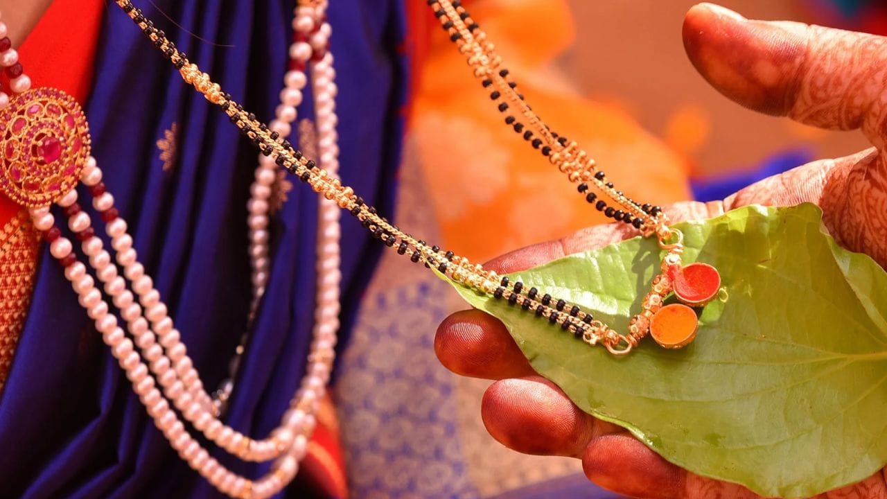 માન્યતા અનુસાર કાળા રંગને નકારાત્મક ઊર્જા અને ખરાબ નજરથી બચાવનાર માનવામાં આવે છે. તેથી મંગળસૂત્રમાં કાળા મણકા ગૂંથવાની પરંપરા શરૂ થઈ હોવાનું કહેવાય છે. એવું માનવામાં આવે છે કે આ મણકા લગ્નિત સ્ત્રી અને તેના પરિવારને નકારાત્મક પ્રભાવોથી સુરક્ષિત રાખવામાં મદદરૂપ બને છે. (Photo Image Credit Source: Giva)