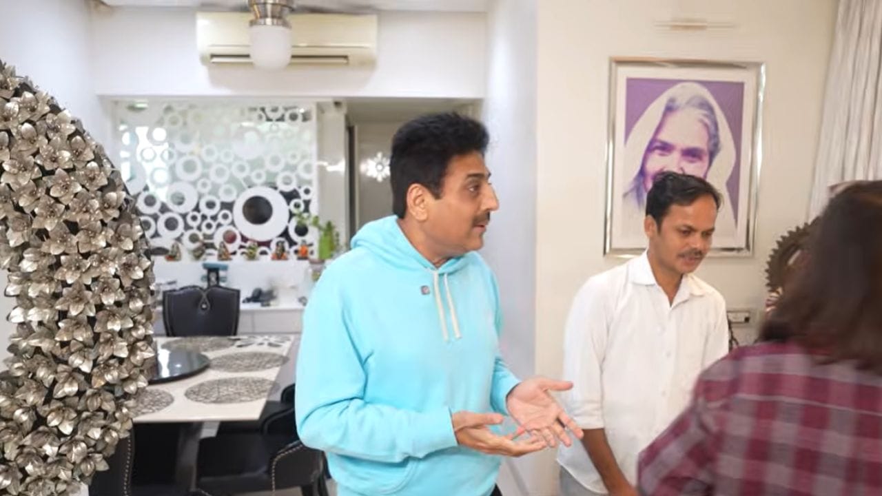 અભિનેતાના ઘરનો લિવિંગ એરિયા એકદમ મોટો છે. સફેદ સોફા છે. દિવાલ પર એક સુંદર પેઇન્ટિંગ પણ છે. (Image Source | Farah Khan, YouTube)